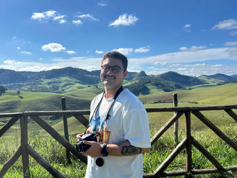 Felipe Lamarca holding a camera in front of rolling green hills