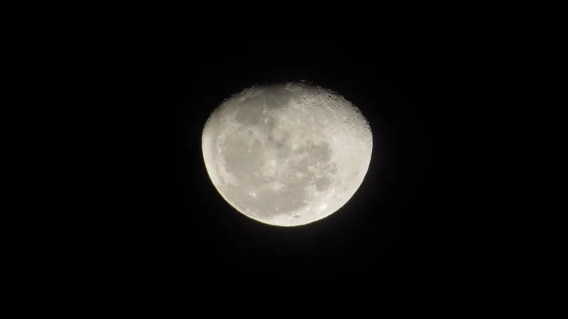 A nearly full moon against a black night sky
